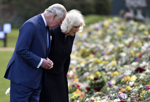 찰스 영국 왕세자와 카밀라 왕세자비가 15일 런던 버킹엄궁 외곽의 말버러 하우스 정원에서 부친 필립공의 별세를 애도하기 위해 시민들이 놓고 간 꽃과 메시지를 들여다보고 있다./연합뉴스