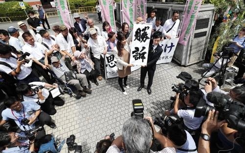 한센병 전 환자의 가족들이 2019년 6월 28일 구마모토지방법원 앞에서 '승소'라고 적힌 펼침막을 들어 보이며 기뻐하고 있다. /교도연합뉴스