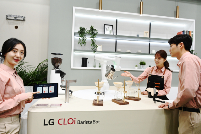 모델들이 LG 클로이 바리스타봇이 핸드드립 커피를 만드는 모습을 살펴보고 있다. 이 로봇은 매 동작을 같은 속도와 시간으로 반복해 항상 일정한 맛과 향의 커피를 제공한다./사진제공=LG전자