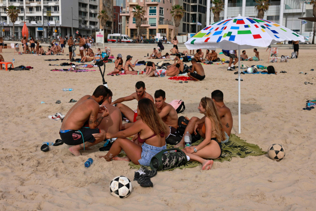 19일(현지시간) 이스라엘 텔아비브의 해변에서 마스크를 쓰지 않은 시민들이 일광욕을 즐기고 있다. /AFP연합뉴스