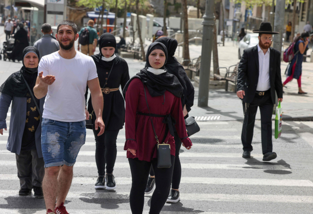 이스라엘이 실외 마스크 착용 의무를 해제한 첫날인 18일(현지시간) 시민들이 마스크를 벗은 채 예루살렘 거리를 걸어가고 있다./AFP연합뉴스