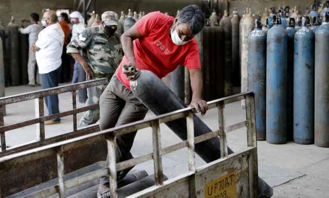 23일(현지 시간) 인도 우타르프라데시주 프라야그라지 외곽의 한 산소 충전소에서 인부들이 충전된 산소통을 트럭에 싣고 있다. /AP연합뉴스