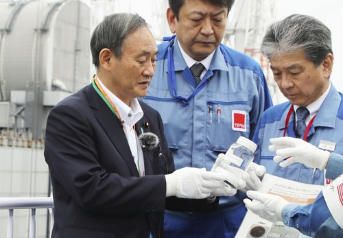 스가 요시히데(菅義偉) 일본 총리가 2020년 9월 26일 일본 후쿠시마(福島) 제1원전에서 정화처리한 방사성 물질 오염수가 든 용기를 들고 있다. 스가 총리는 당시 다핵종(多核種)제거설비(ALPS)로 거른 오염수를 