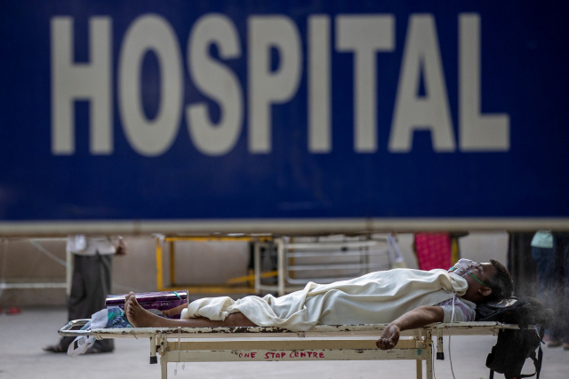 지난 23일(현지시간) 인도 수도 뉴델리의 그루 테그 바하두르 병원 밖에서 한 코로나19 환자가 입원을 기다리며 임시 병상에 누워 있다./로이터연합뉴스