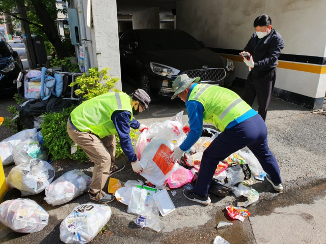 감시원들이 불법 투기한 쓰레기를 추적 하고 있는 모습