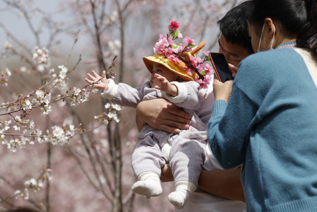 중국 베이징의 한 공원에서 부모가 아이의 사진을 찍어주며 휴일을 즐기고 있다. /AP연합뉴스