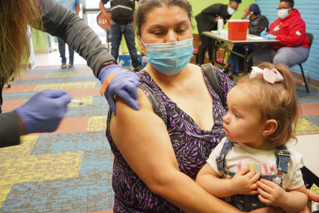 4월 30일(현지시간) 미국 텍사스주 패서디나에서 아이를 안고 있는 한 여성이 코로나19 백신 주사를 맞고 있다. /패서디나=AFP연합뉴스