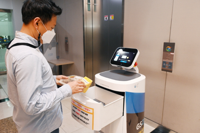 한 직장인이 4일 서울 강남구 역삼동 GS타워에서 실내 로봇 'LG 클로이 서브봇’이 배송한 물품을 받고 있다. /사진 제공=LG전자
