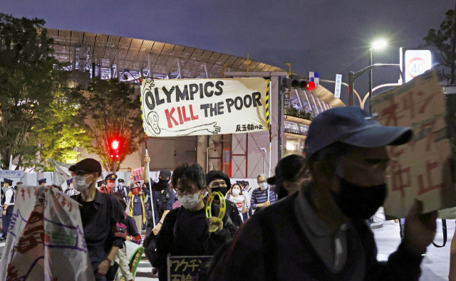 도쿄올림픽 개최에 반대하는 일본 시민들이 지난 9일 올림픽 육상경기 테스트 대회가 열린 도쿄 신주쿠 국립경기장 주변에서 팻말을 들고 시위를 벌이고 있다./로이터연합뉴스