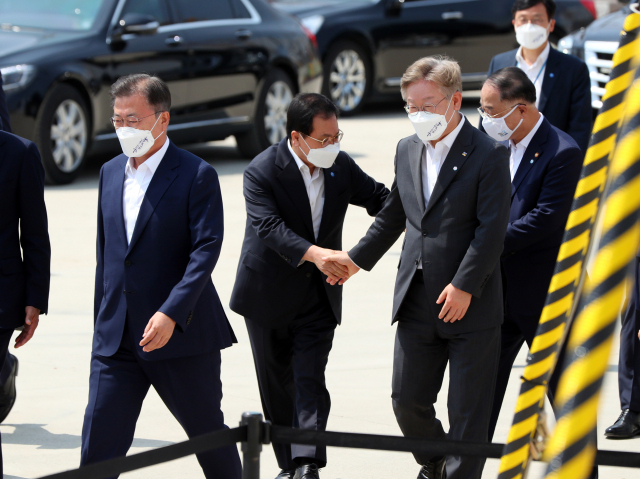 문재인 대통령이 13일 오후 경기도 평택시 삼성전자 평택단지 3라인 건설 현장에 마련된 야외무대에서 열린 'K-반도체 전략 보고'에 참석하고 있다. 문 대통령 뒤에서 유영민 청와대 비서실장이 이재명 경기도지사, 홍남기 경제부총리와 인사하고 있다. /연합뉴스