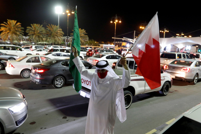 17일(현지시간) 사우디아라비아와 바레인을 연결하는 고속도로인 킹 파즈 코즈웨이에서 한 바레인 남성이 두 국가의 국기를 들고 바레인으로 향하는 차량을 환영하고 있다. 이날 사우디아라비아는 자국민의 해외여행 금지를 해제했다. /로이터연합뉴스