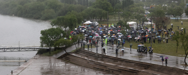16일 오후 서울 반포한강공원 수상택시 승강장 인근에서 열린 '고 손정민 군을 위한 평화집회'에서 참가자들이 우산을 쓴 채 자리를 지키고 있다. /연합뉴스