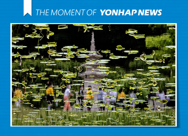 부처님오신날을 앞둔 18일 경기도 남양주시 봉선사에서 어린이들이 탑 주변을 돌아보는 모습이 연못에 투영되고 있다. /연합뉴스