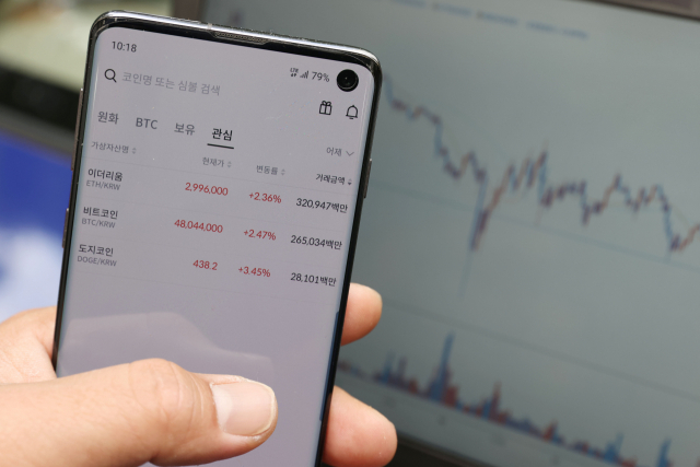 23일 오전 한 투자가가 휴대폰으로 암호화폐 시세를 들여다 보고 있다./연합뉴스