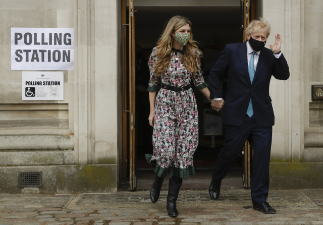 보리스 존슨 영국 총리가 지난 6일(현지시간) 런던의 한 지방선거 투표소에서 약혼녀 캐리 시먼즈와 함께 투표한 뒤 나오면서 손을 흔들고 있다./AP연합뉴스