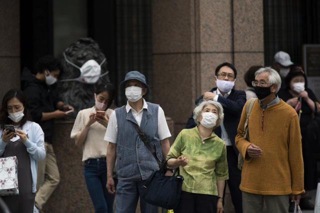 21일 일본 도쿄 긴자 쇼핑가의 한 교차로에서 마스크를 쓴 행인들이 보행신호를 기다리고 있다. /AP연합뉴스