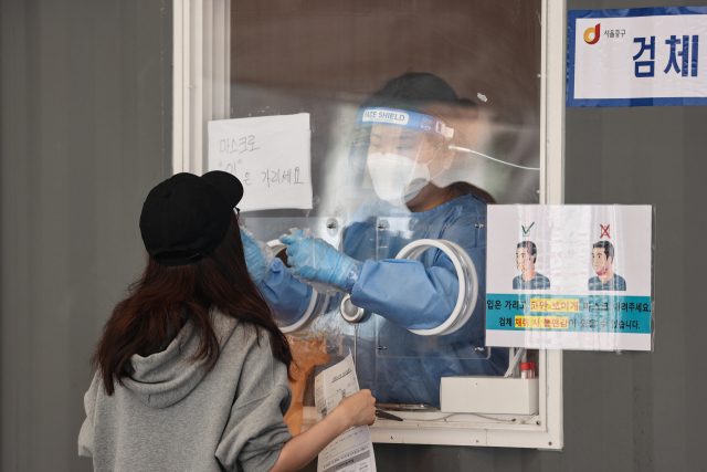 19일 오전 서울역광장에 마련된 임시선별진료소에서 의료진이 검체채취를 하고 있다. /연합뉴스