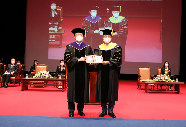 문주현(오른쪽) 엠디엠그룹 회장이 장제국 동서대 총장으로부터 명예부동산학 박사학위를 받고 기념촬영을 하고 있다./사진제공=동서대