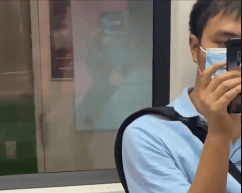 지난 17일(현지시간) 싱가포르 지하철에서 한 남성이 얼굴 높이로 휴대전화를 들고 있다. 맞은 편에 앉아있던 여성은 이 남성이 자신을 찍는 모습을 뒷쪽 유리창을 보고 확인하고 경찰에 신고했다./ 출처=트위터 cathariiine