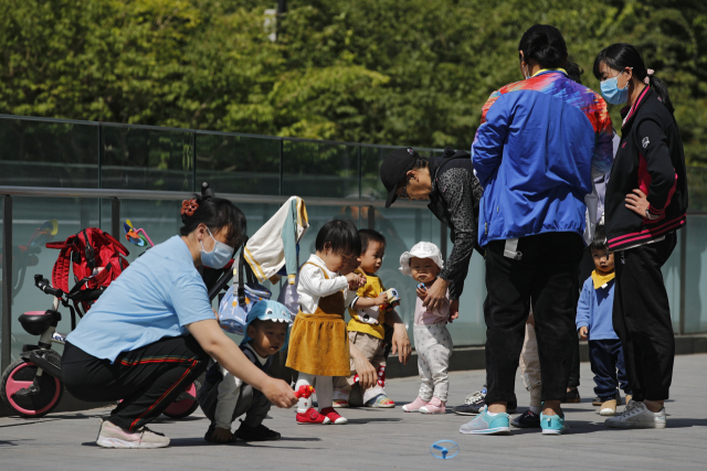 지난달 10일 베이징의 사무실 빌딩 주변에서 주민들이 아이들과 함께 시간을 보내고 있다. /AP연합뉴스