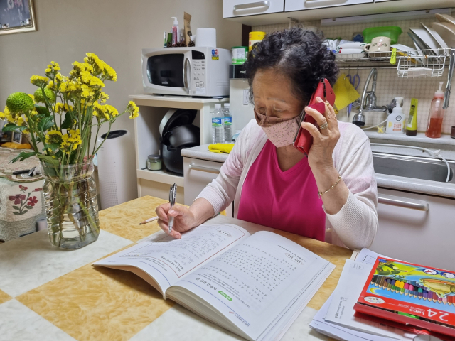 서울 노원구의 ‘데일리 홈런’ 프로그램에 참여한 주민이 전화를 받으며 학습지를 읽고 있다. /사진 제공=노원구