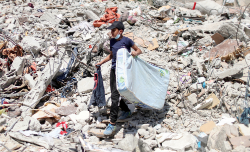 팔레스타인 자치지역인 가자지구의 중심도시 가자시티에서 2일(현지시간) 한 어린이가 이스라엘군 공습으로 폐허가 된 주택의 잔해 위에서 매트리스를 옮기고 있다. /로이터연합뉴스
