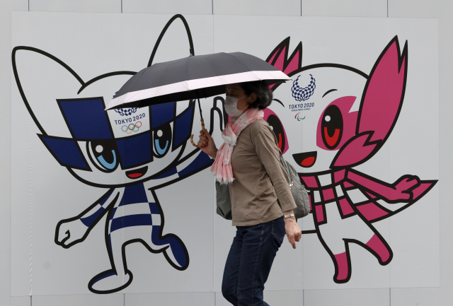 지난달 28일 도쿄 올림픽 마스코트인 미라이토와와 패럴림픽 마스코트인 소메이티 앞을 한 여성이 지나가고 있다. /로이터연합뉴스