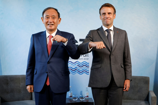 영국 콘월에서 열린 주요 7개국(G7) 정상회의에 참석 중인 스가 요시히데(왼쪽) 일본 총리와 에마뉘엘 마크롱 프랑스 대통령이 12일 오후(현지시간) 양자 회담에 앞서 팔꿈치 인사를 하고 있다./AFP연합뉴스