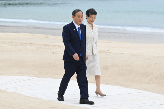 주요 7개국(G7) 정상회의가 개막한 11일(현지시간) 스가 요시히데 일본 총리와 부인 마리코 여사가 기념사진 촬영을 위해 걷고 있다./ AFP연합뉴스