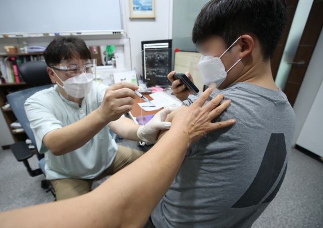 지난10일 서울 동작구 경성의원에서 한 시민이 얀센 백신을 접종받으며 휴대전화로 인증샷을 찍고 있다./연합뉴스