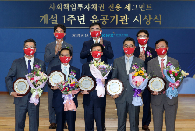 손병두(뒷줄 왼쪽 두번째) 한국거래소 이사장과 각 수상 기업 대표들이 15일 한국거래소 서울사옥에서 열린 ‘SRI채권 전용 세그먼트 개설 1주년 행사'에 참여해 기념 촬영을 하고 있다. / 사진제공=한국거래소