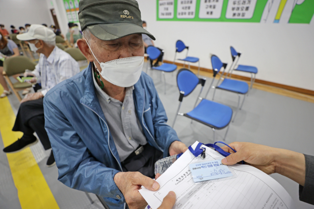 17일 오전 서울 영등포구 영등포아트홀에 마련된 코로나19 예방접종센터에서 어르신이 백신 접종 완료 카드와 예방접종증명서를 받고 있다./연합뉴스