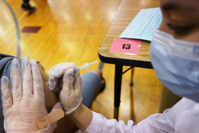영국 런던의 한 한교에 마련된 접종소에서 한 의료인이 지난 11일 화이자 백신을 주사하고 있다. /AP연합뉴스