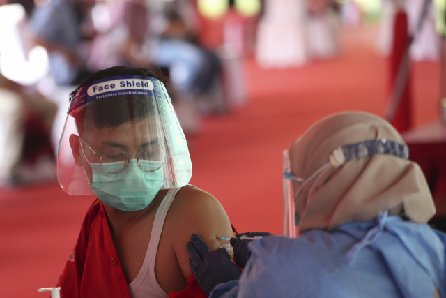 인도네시아 자카르타 외곽 브카시의 패트리엇 칸드라바가 스타디움에 마련된 신종 코로나바이러스 감염증(코로나19) 백신접종소에서 14일(현지시간) 마스크와 얼굴가리개를 착용한 한 남성이 중국산 시노백 백신을 접종받고 있다./AP연합뉴스