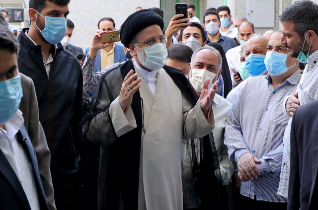 이란의 강경보수 대선 후보인 에브라힘 라이시가 18일(현지시간) 수도 테헤란의 투표소에서 지지자들에 둘러싸여 있다. 라이시는 득표율 61.9%로 당선을 확정지었다./AFP연합뉴스