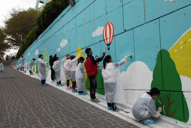 메리츠 참사랑 봉사단 소속 임직원이 가족들과 함께 서울의 한 초등학교에서 벽화그리기 봉사활동을 펼치고 있다. /사진제공=메리츠증권