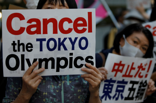 도쿄올림픽 개막이 한 달 앞으로 다가온 지난 23일 일본 도쿄도청 앞에서 시민들이 '도쿄올림픽 취소하라'고 적힌 피켓을 들고 시위를 벌이고 있다. /로이터연합뉴스