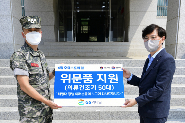 오진석(오른쪽) GS리테일 편의점사업부장(부사장)과 연평부대장이 해병대 장병에게 의류 건조기를 기증하고 기념사진을 찍고 있다./사진 제공=GS리테일