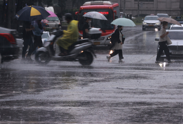 23일 오후 서울 중구 회현사거리에서 시민들이 소나기에 우산을 쓴 채 횡단보도를 건너고 있다. /연합뉴스