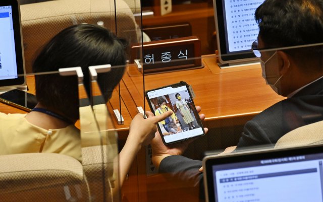 류호정(왼쪽) 정의당 의원이 24일 서울 여의도 국회 본회의장에서 자신의 옷차림에 관한 한 사진 뉴스를 보며 허종식 더불어민주당 의원과 대화하고 있다. /성형주 기자