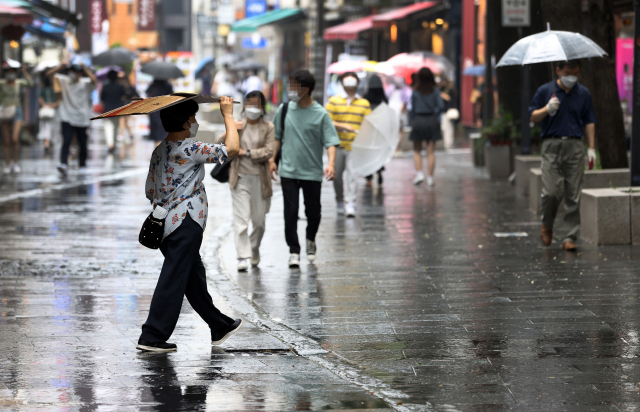 소나기가 내린 지난 23일 오후 서울 종로구 인사동 거리에서 한 시민이 종이상자로 비를 피하고 있다. /연합뉴스