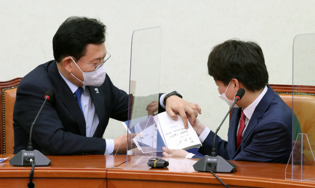 송영길(왼쪽) 더불어민주당 대표가 지난 17일 이준석 국민의힘 대표의 예방을 받으며 자신의 저서를 선물하고 있다. / 성형주 기자