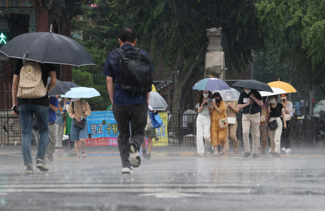 소나기가 내린 29일 오후 서울 광화문 사거리에서 시민들이 비를 맞으며 걸어가고 있다. /연합뉴스
