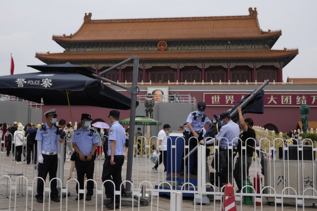 중국이 다음 달 1일 공산당 창당 100주년 기념일 행사 준비에 나선 가운데 23일 베이징 톈안먼 광장 입구에 경찰이 우산을 설치하고 있다. 행사 준비를 위해 톈안먼 광장은 폐쇄됐다. /AP연합뉴스