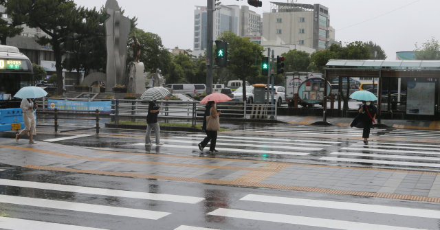 3일 오전 장마전선의 영향으로 제주지방에 비가 내리는 가운데 시민들이 우산을 쓰고 횡단보도를 건너가고 있다. /연합뉴스