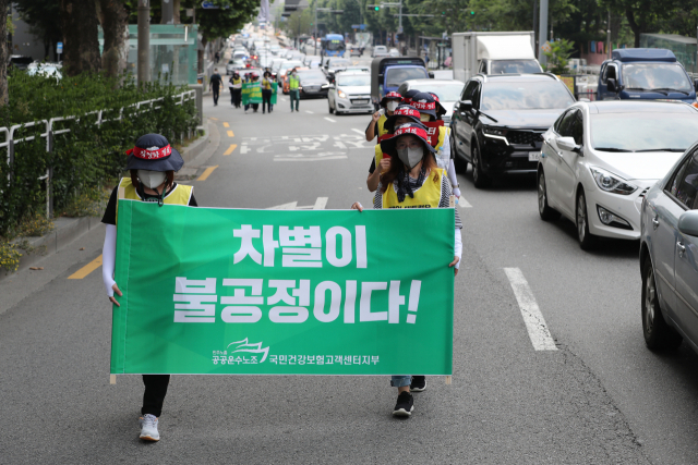 공공운수노조 국민건강보험 고객센터지부 소속 조합원들이 지난 달 23일 서울시 마포대로 공덕에서 충정로 쪽으로 공공부문 비정규직의 직접고용을 촉구하는 손피켓과 플래카드를 들고 거리행진을 벌이고 있다./연합뉴스