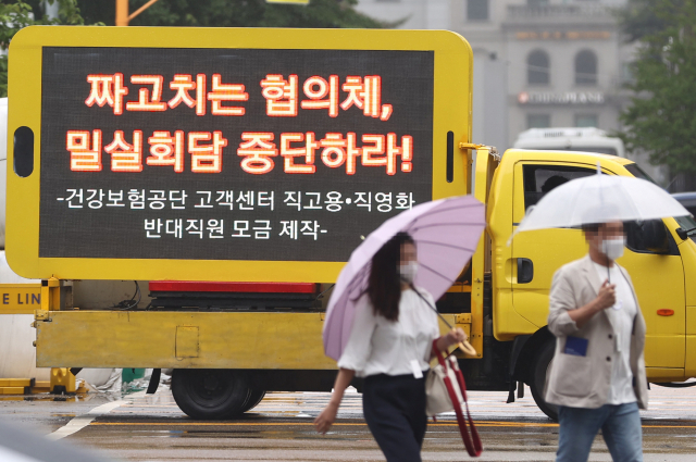 지난 달 18일 국민건강보험공단 제3차 사무논의협의회가 열리는 여의도 한 호텔 앞에 주차된 국민건강보험공단 직원들의 시위트럭에 고객센터 직원 직고용 반대 메시지가 적혀 있다./연합뉴스