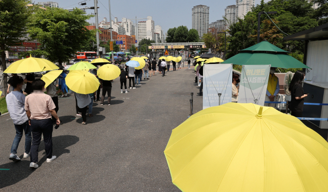 지난 2일 오후 서울 서초구 고속버스터미널 앞 코로나19 선별검사소에서 시민들이 서초구청이 제공한 우산을 쓰고 검사 대기를 하고 있다./연합뉴스