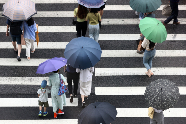 전국에 비가 내리며 장마가 시작된 3일 오후 서울 마포구 홍대입구역 인근에서 시민들이 우산을 쓰고 길을 건너고 있다. /연합뉴스