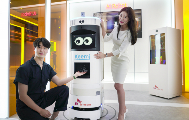 SK텔레콤 모델들이 5일 서울 삼성동 코엑스 이벤트홀에서 진행되는 5세대 이동통신(5G) 28GHz 시범 서비스 중 하나인 인공지능(AI)방역로봇을 통해 체온을 측정하고 손 소독제를 받는 과정을 소개하고 있다. /사진 제공=SK텔레콤